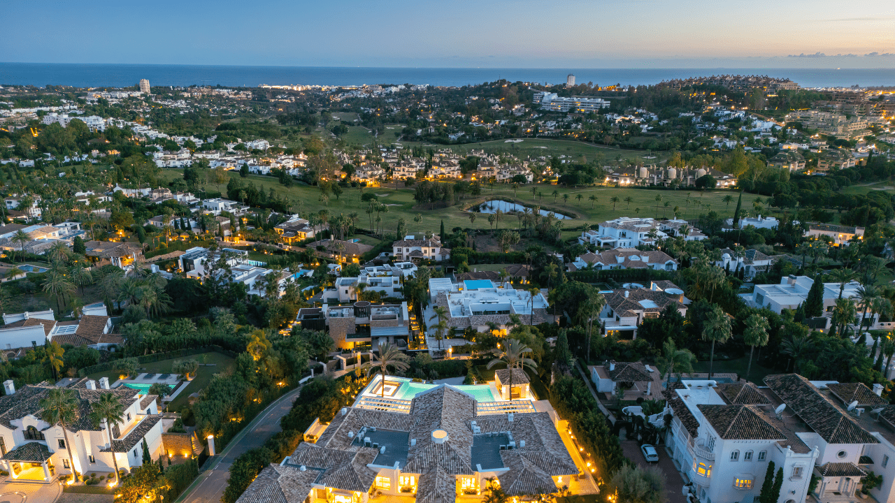 Stunning aerial view of La Cerquilla, Marbella, showcasing luxury villas surrounded by lush greenery and the Mediterranean Sea in the background