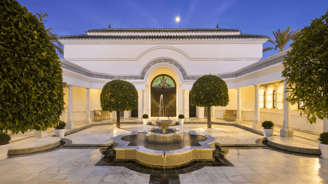 Majestic courtyard of a Nueva Andalucía palace with a central fountain, orange trees, and elegant arches