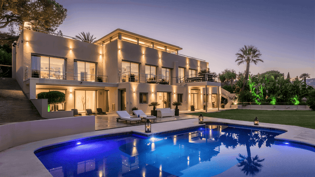 Luxurious villa for sale in Nueva Andalucia with a modern design, private pool, spacious terraces, and lush landscaped gardens at sunset