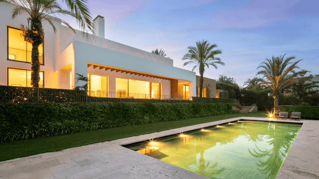 Luxury villa for sale at Finca Cortesin resort with illuminated pool and palm trees